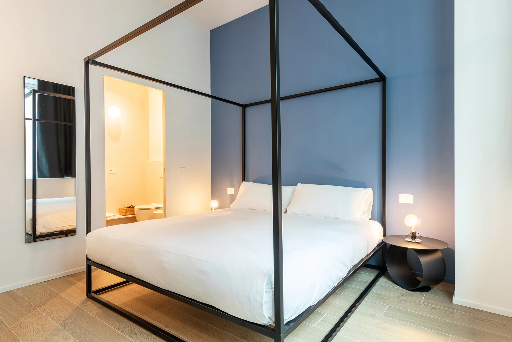 Camera da letto con letto a baldacchino nero e lenzuola bianche