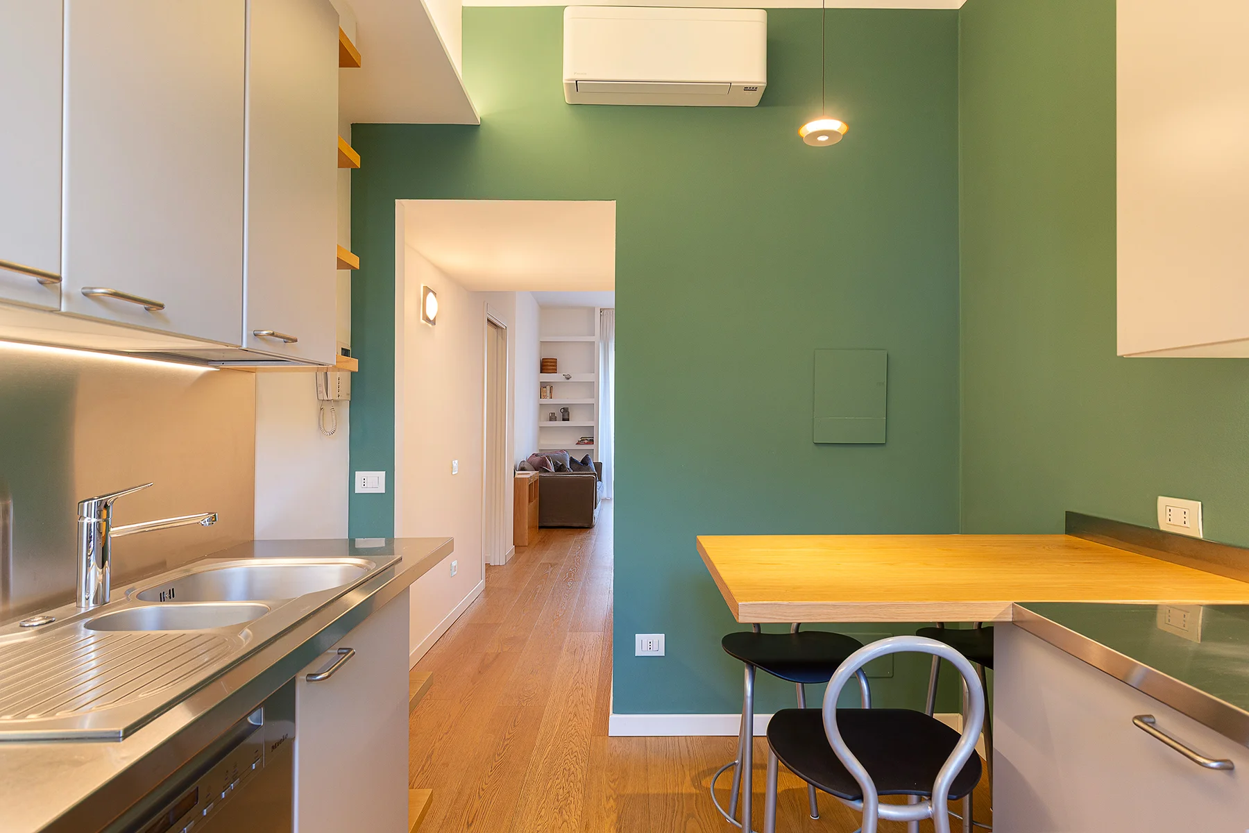 Cucina abitabile con bancone e pareti verdi appartamento Milano