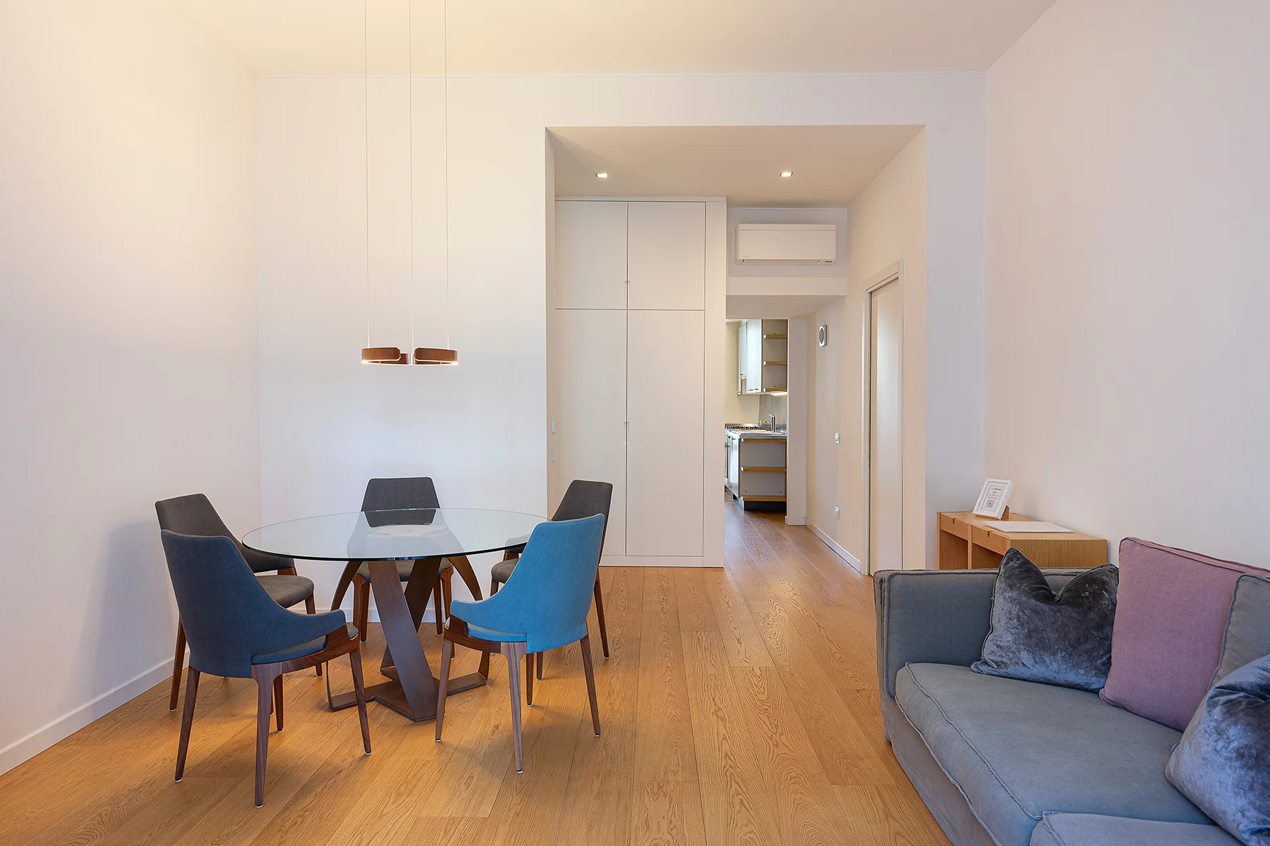 Soggiorno luminoso Erculea apartment con tavolo in vetro e sedie blu