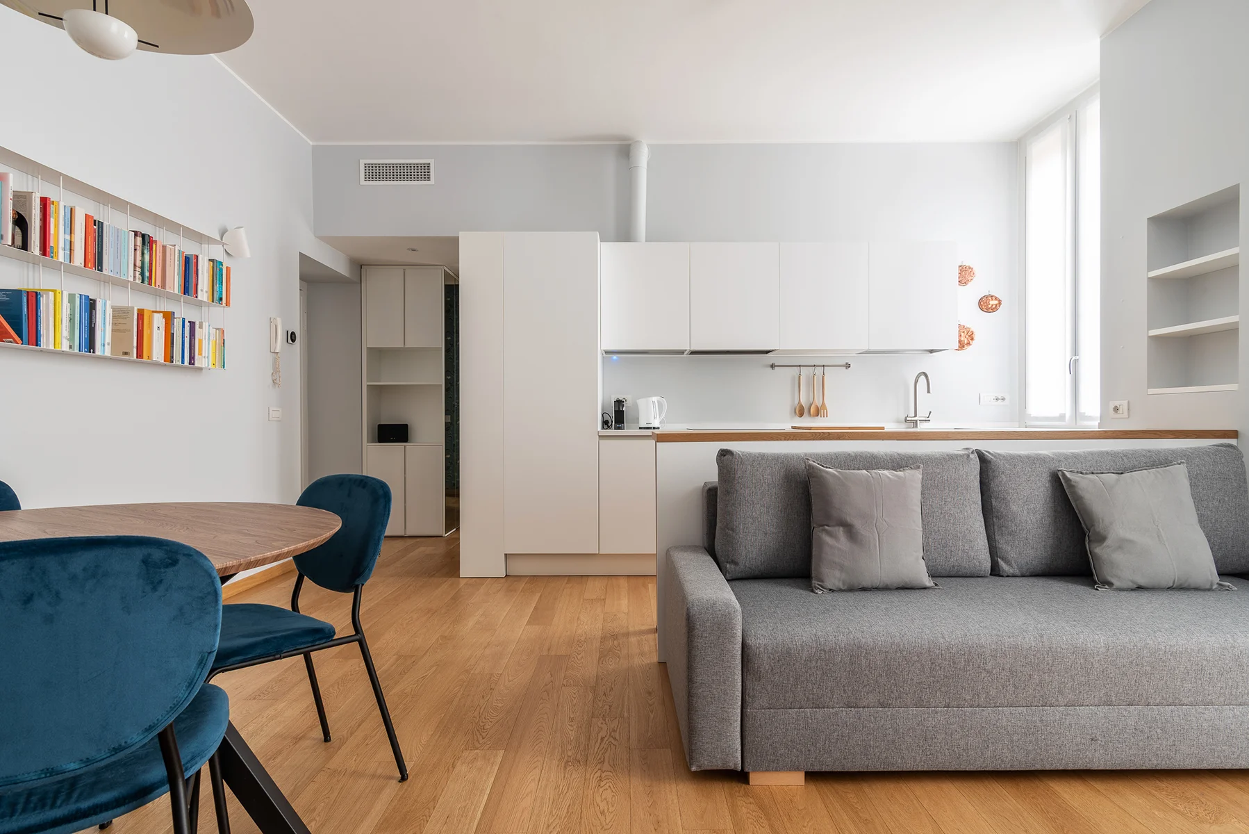 Soggiorno luminoso Eustachi apartment con libreria a parete e sedie blu