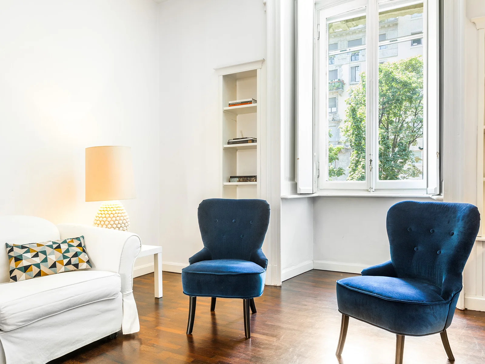 Soggiorno luminoso Majno apartment con poltrone blu velvet e divano bianco