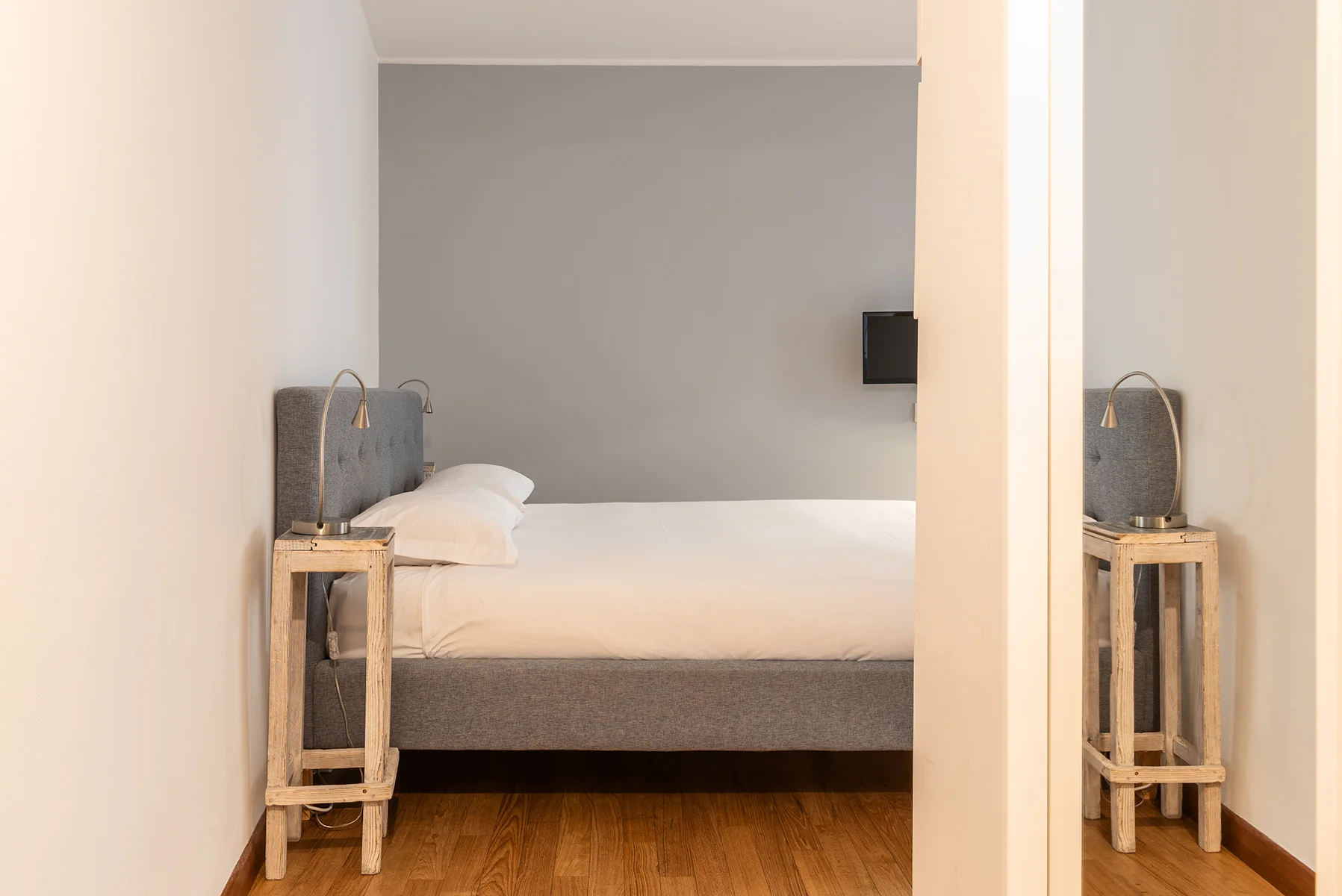 Camera matrimoniale Spiga Suite 1 con testiera grigia e parquet