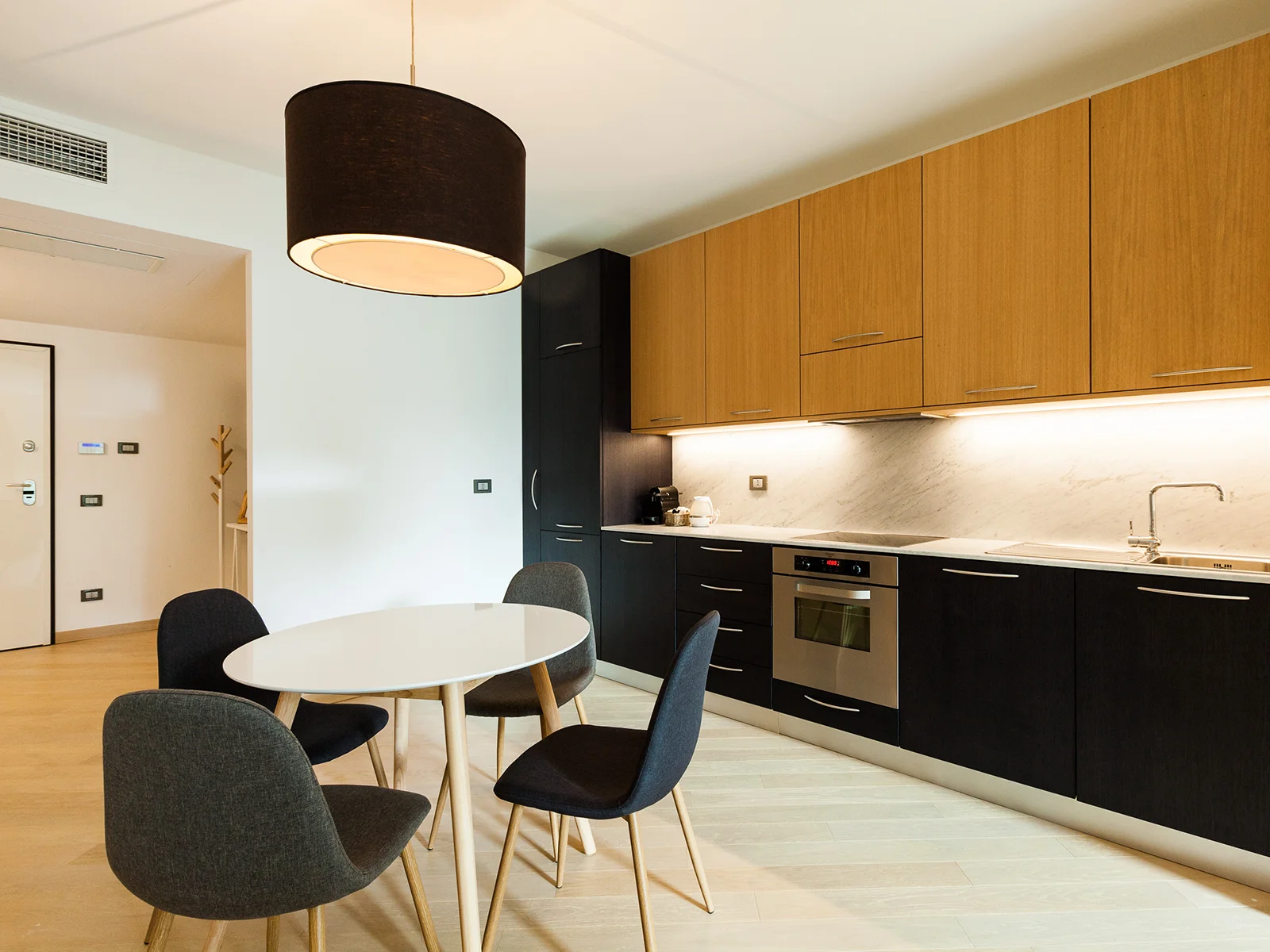 Zona pranzo con sedie scure e cucina attrezzata